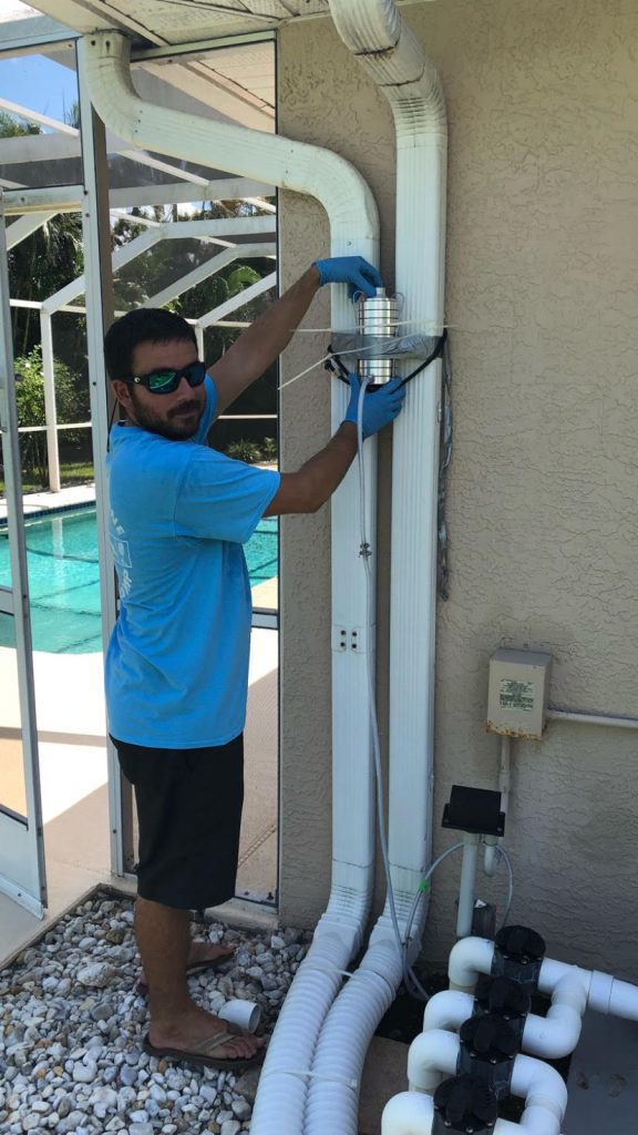 Florida Gulf Coast University graduate student Adam Catasus installs an algae air-sampling pump outside a Cape Coral home. 