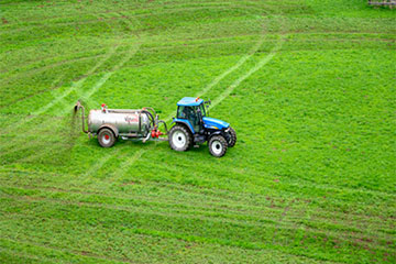 Tractor pulling a tank in a green field