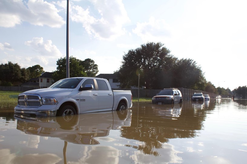 A row of vehicles parked along a flooded road.