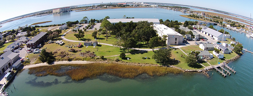 Aerial view of a NOAA facility along the coast with docks. A living shoreline is to the left and a hardened shoreline to the right.