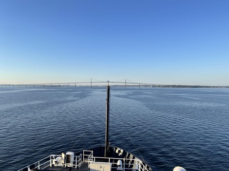  View over the bow of a ship looking towards a suspension bridge in the distance