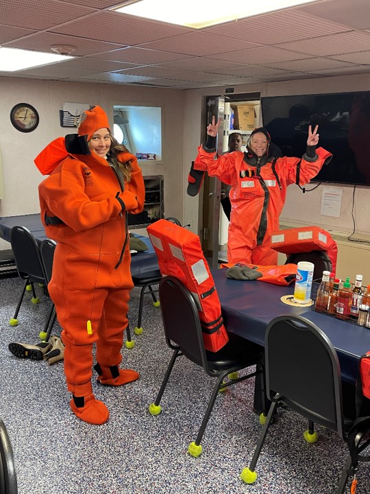 two people wearing spongy orange suits smile at the camera.