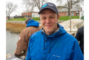 Man in blue hat and raincoat smiling at camera