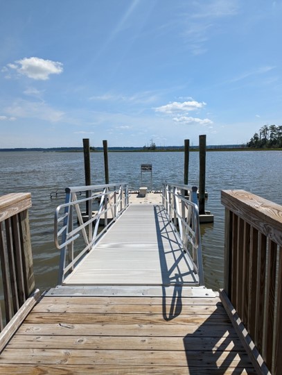 Wooden walk leading to a boat ramp leading to a floating boat launch.