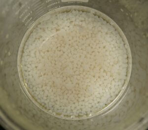 small, white beads in a beaker of liquid