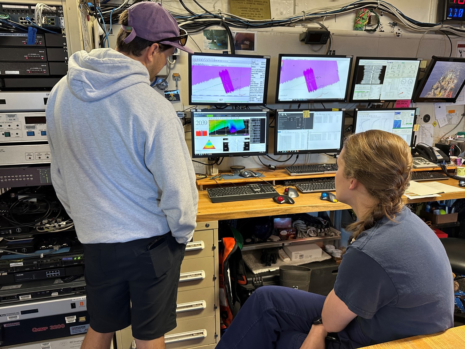  two scientists look at several computer screens showing multibeam sonar data
