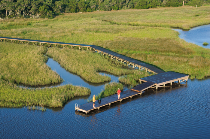 aerial view of a dock coming out into the water from a marsh