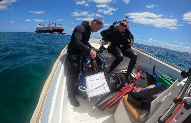 Two researchers in small boat prepare to SCUBA dive coastal water near Port Everglades to survey queen conch.