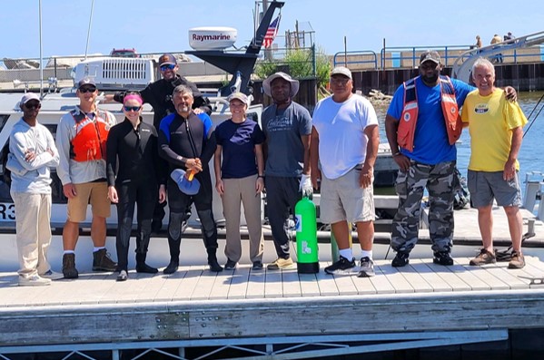 Group of people standing on a dock in front of a boat.