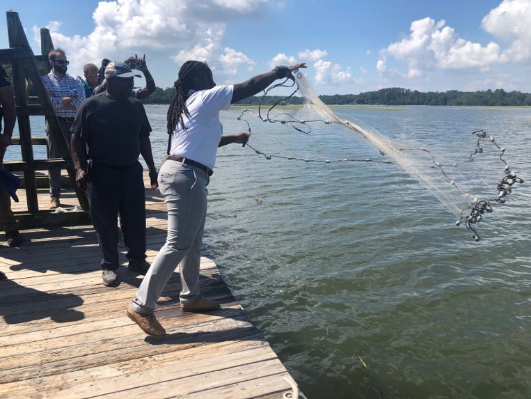 Person on a dock throws a cast net into the water