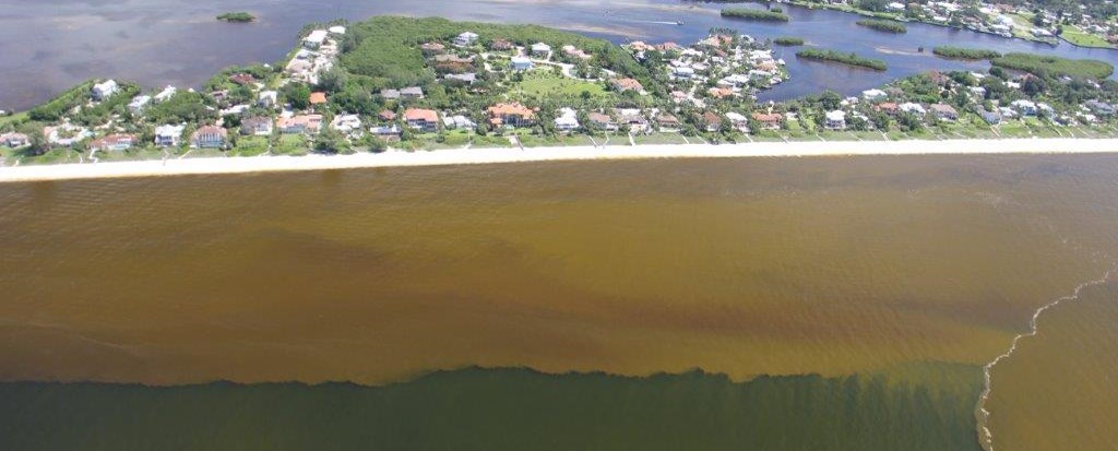 Aerial view of coastal area with reddish brown plume lining the coast