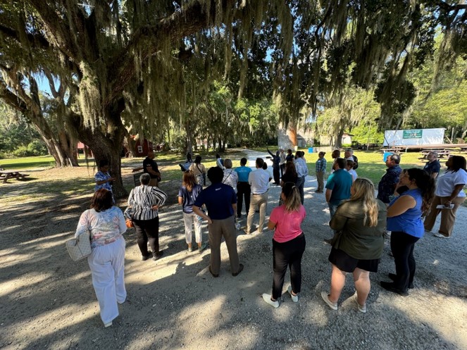 Group of people standing on a shaded dirt path 