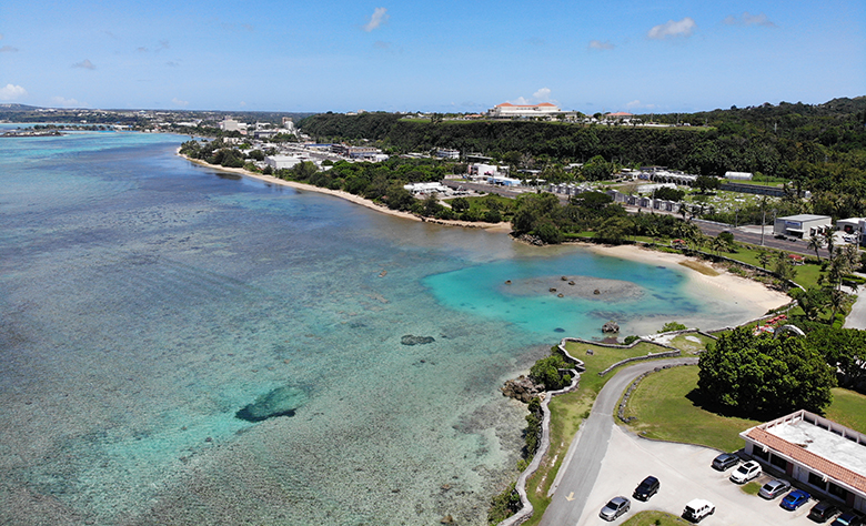 A shallow coral reef borders a coastline in Guam.