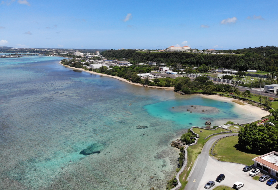 A shallow coral reef borders a coastline in Guam.