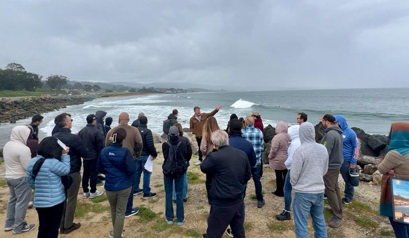 Large group of people standing on bluff overlooking Surfer's Beach in Half Moon Bay, California.