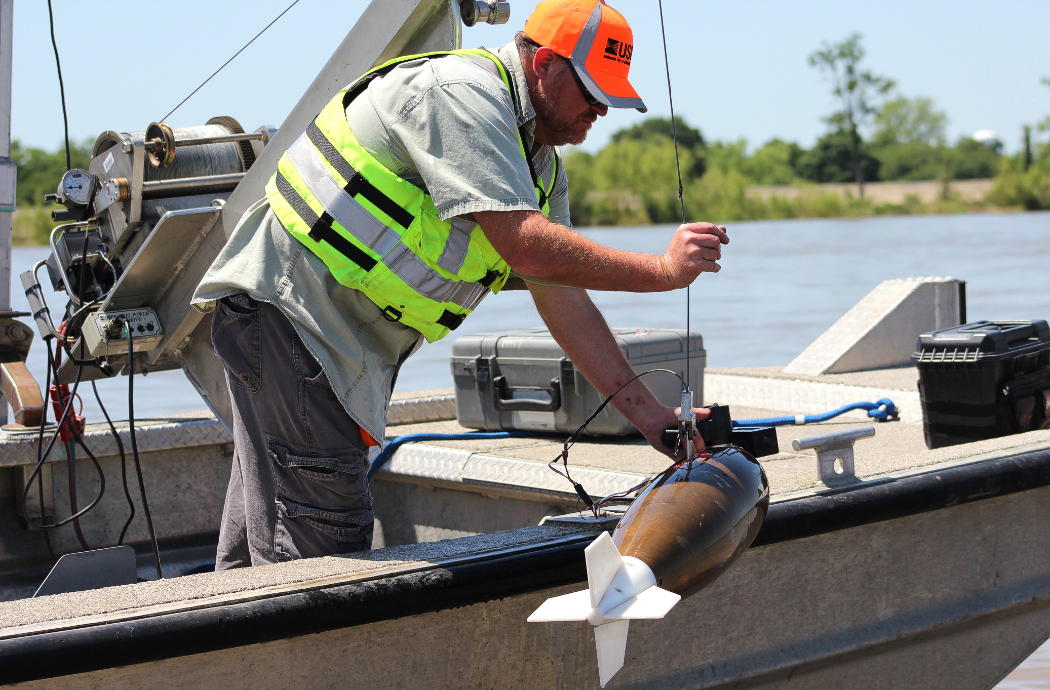 man deploys scientific equipment over side of boat to take a water sample