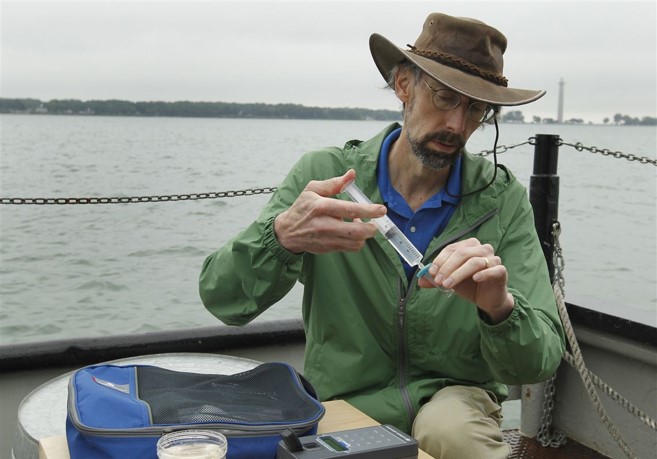 Scientist near a body of water injects liquid into a small tube